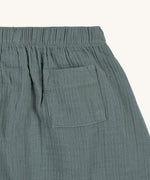 A closeup of the Lassig GOTS organic cotton muslin trousers in petrol green.
