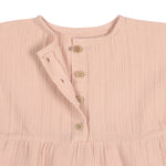 A closeup of the brown buttons on the Lassig organic cotton muslin dress for babies and toddlers in a pretty powder pink colour.