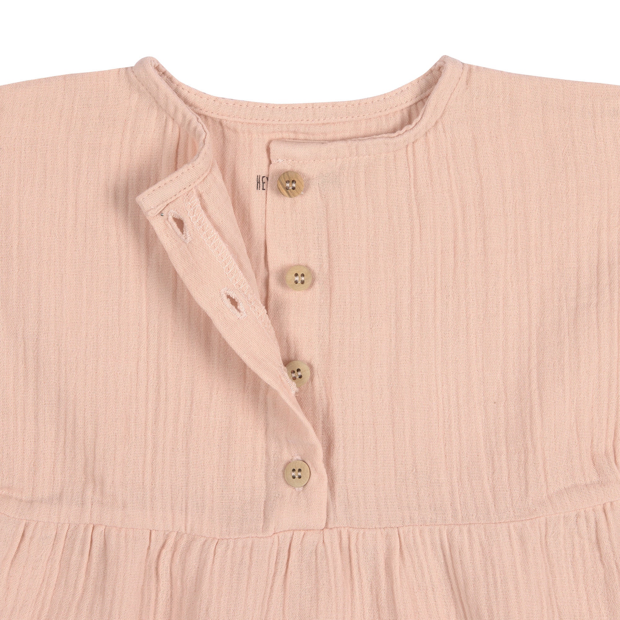 A closeup of the brown buttons on the Lassig organic cotton muslin dress for babies and toddlers in a pretty powder pink colour.