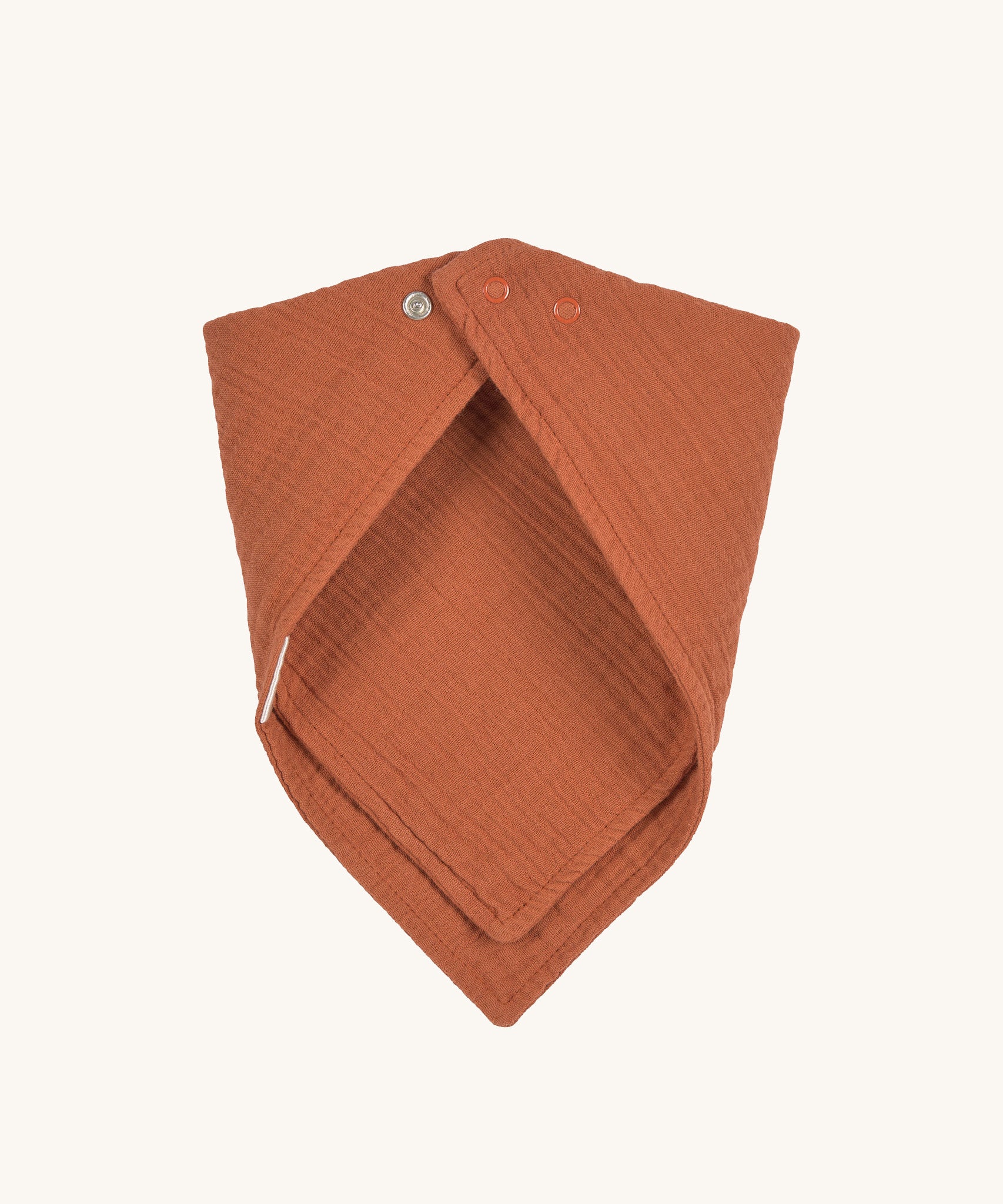 The Lassig organic cotton muslin bandana dribble bib in a lovely orange rust colour, with little metal push-in fastenings at the neck.