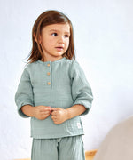 A little girl wearing the Lassig organic cotton muslin long sleeved shirt for babies and toddlers, in a silver grey