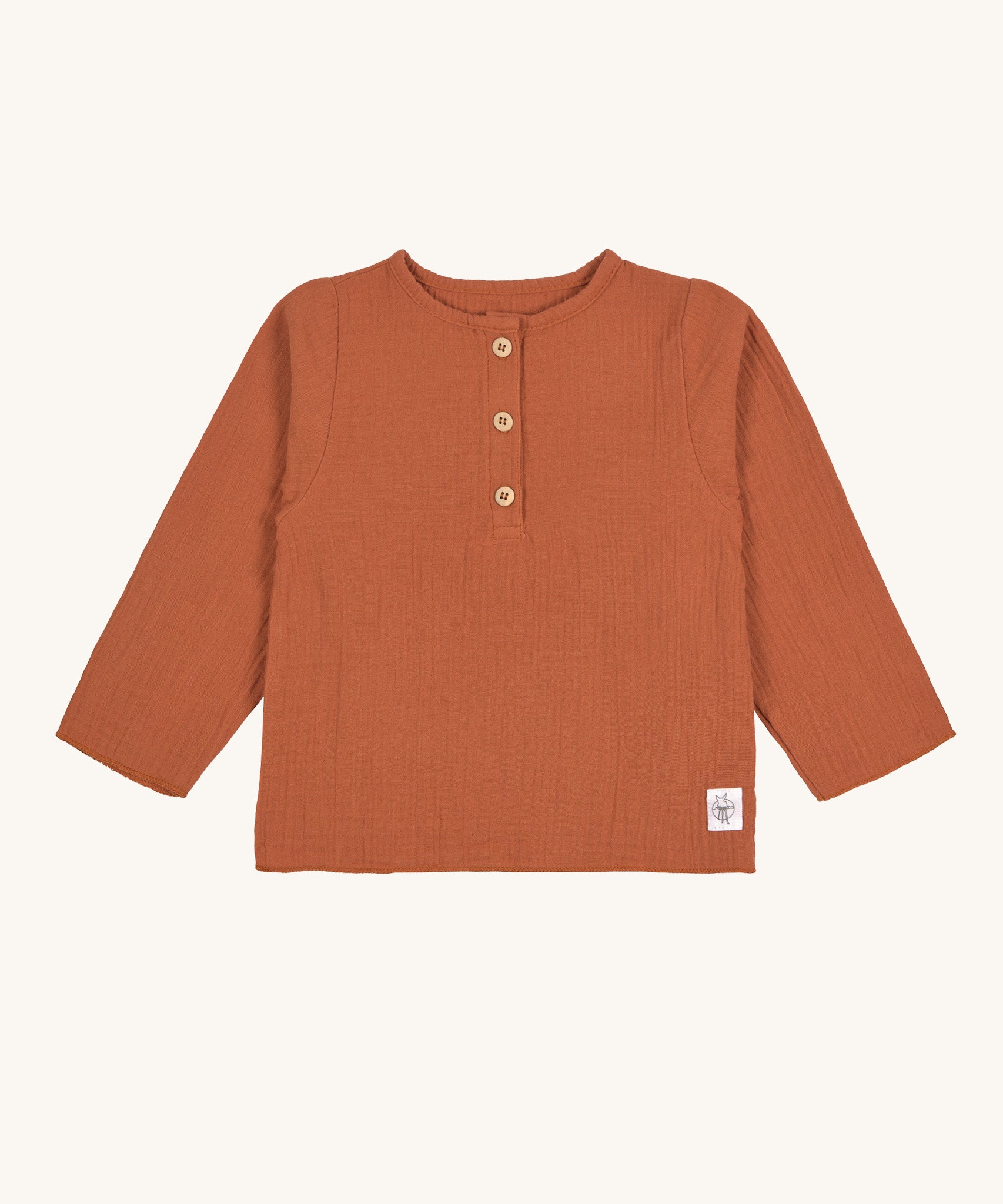 The Lassig organic cotton muslin shirt for babies and toddlers, in a bright orange rust colour with little brown buttons.