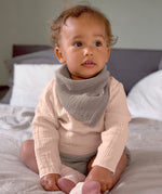 A baby wearing the Lassig organic cotton muslin long sleeved top, in a beautiful pale powder pink colour.