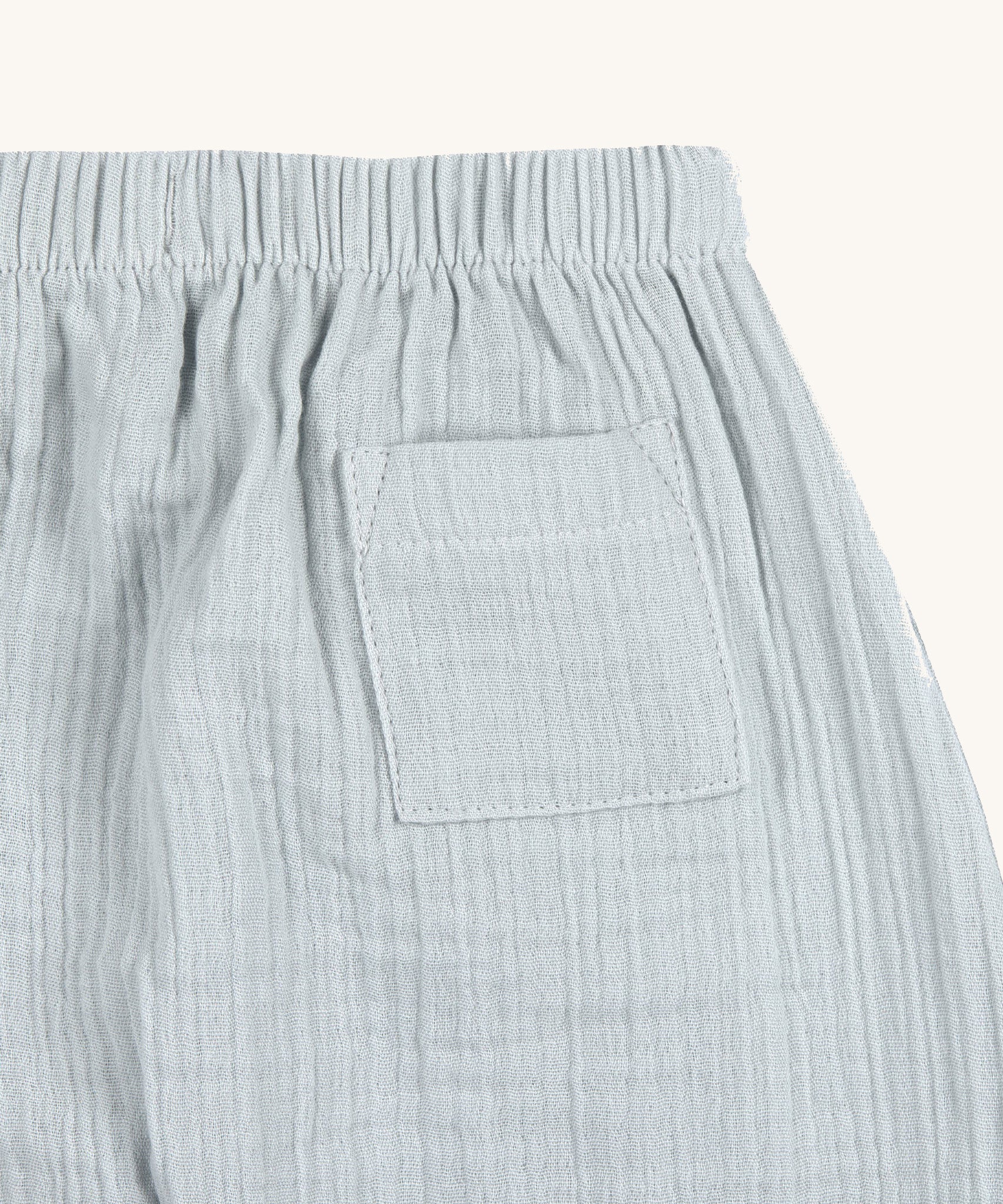 A closeup of the back pocket on the Lassig organic cotton muslin baby pants, in powder blue. 