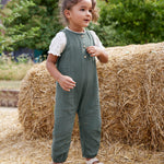 A child wearing the lassig organic cotton muslin jumpsuit in petrol green. 