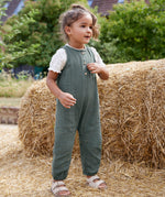 A child wearing the lassig organic cotton muslin jumpsuit in petrol green. 