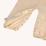 A closeup of the press-in metal fastenings around the leg area of the Lassig organic cotton muslin jumpsuit. 