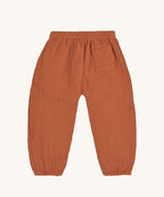 The back of the Lassig organic cotton muslin pants in an orange rust colour. 