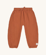 The Lassig organic cotton muslin baby pants in an orange rust colour. 