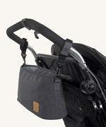 The Lassig pram buggy organiser bag in anthracite, hanging on a stroller with the included clip hooks.