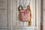 The Lassig rolltop nappy change backpack in cinnamon, hanging on a coat hook