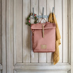 The Lassig rolltop nappy change backpack in cinnamon, hanging on a coat hook