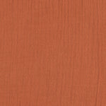 A closeup of the Lassig organic cotton muslin bandana dribble bib in a lovely orange rust colour