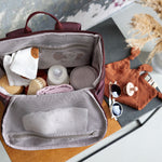 A top view of an opened Lassig Slender Up Nappy change backpack, with a baby bottle, cloths, and more inside.