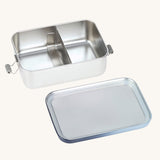 The Lassig Stainless Steel Lunchbox with a Unique Dark Blue lid show with the lid off and divider in place in the box. This lunch box has a removable divider. 