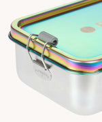 A close up of the clamp latch closure on the Lassig Stainless Steel Lunchbox in a  Solid Bold Rainbow design. A stainless steel lunchbox with removable divider featuring an iridescent rainbow coloured lid. This lunchbox is part of a wide range of reusable items available at Babipur. 