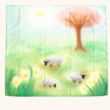 play cloth with a green spring meadow, sheep grazing, daffodils growing, a tree and sun shining. 