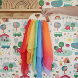 Laura's Play Cotton large Wooden Display holder with heart cut out with 7 play cloths inside placed on a peg shelf.