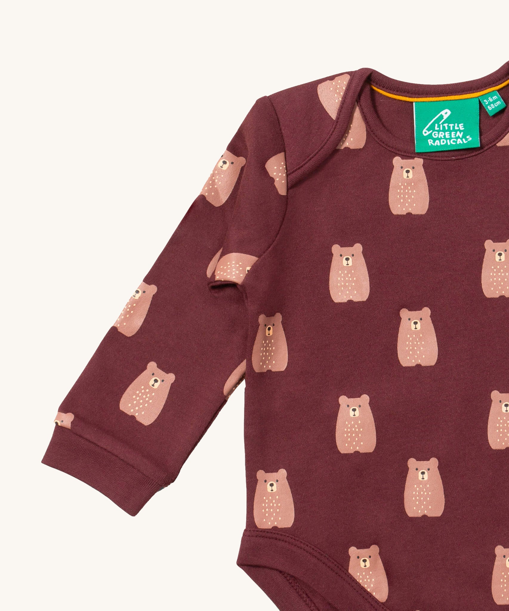 A close up of the brown bear Little Green Radicals baby body suit showing the dark maroon trim and cute brown bear print on soft organic cotton fabric
