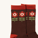 A close up of the Little Green Radicals flowers ankle showing the retro flowers inspired design on brown organic cotton fabric with light brown trim.
