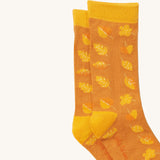 A close up of the Little Green Radicals golden leaves ankle showing the yellow autumn inspired  leaves design on orange organic cotton fabric with yellow trim.