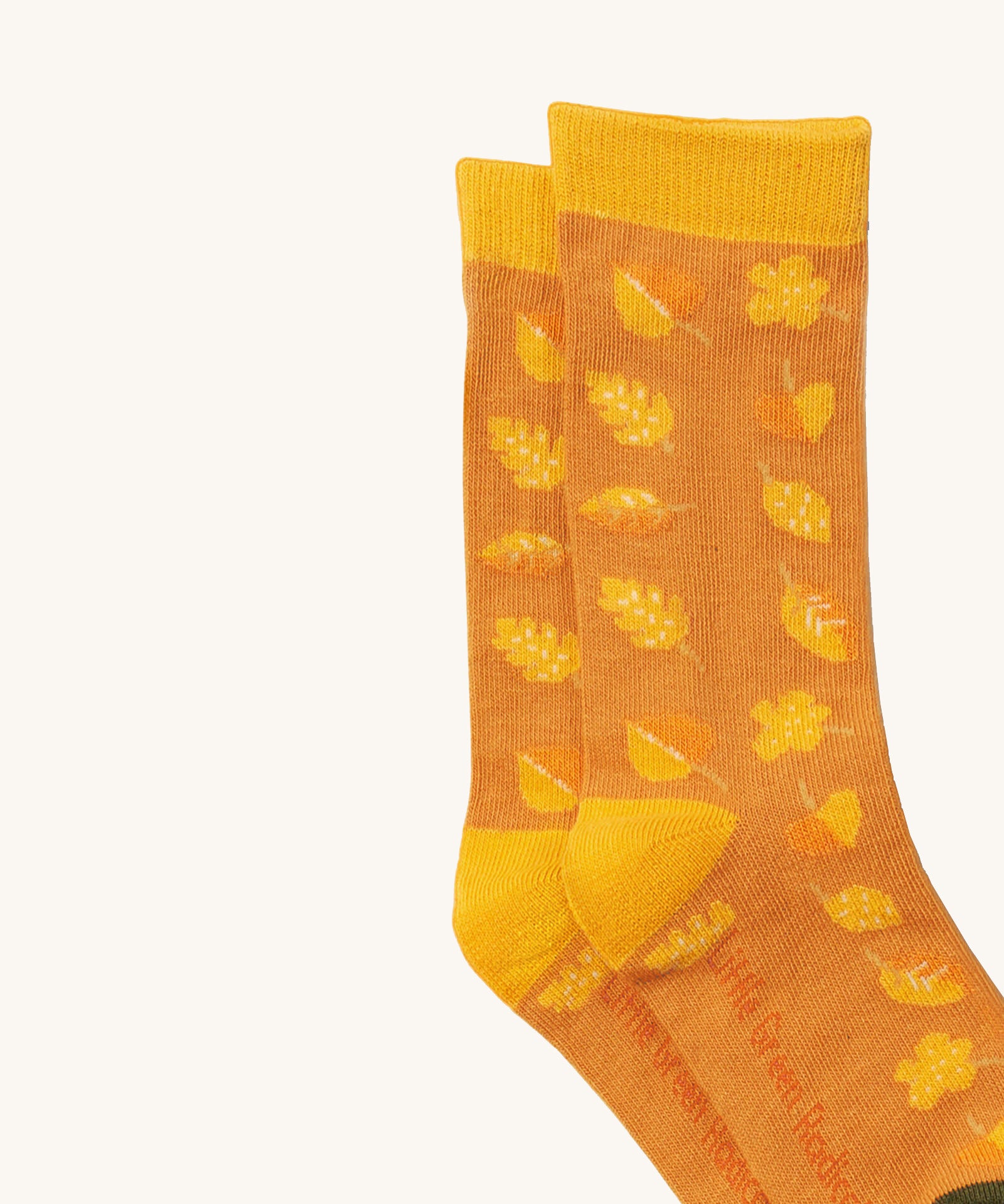 A close up of the Little Green Radicals golden leaves ankle showing the yellow autumn inspired  leaves design on orange organic cotton fabric with yellow trim.