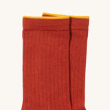 A close up of the red Little Green Radicals  ankle sock. Showing the soft ribbed stitch and yellow trim on organic cotton fabric.