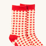 A close up of the red and white checked Little Green Radicals ankle socks check detail with red trim on organic cotton fabric.