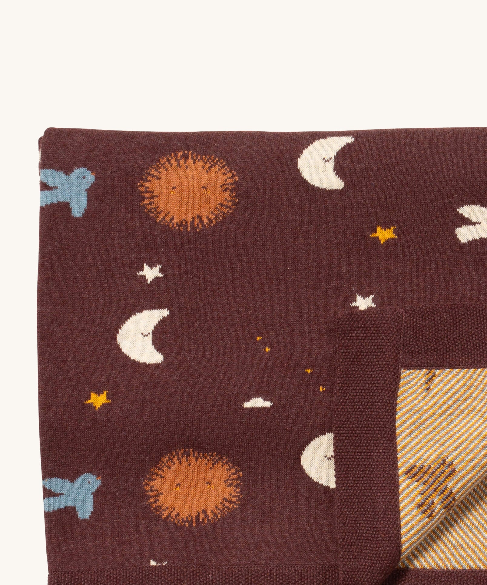 A close up of the Little Green Radicals baby blanket in flying birds. Showing the design detail and yellow striped embroidery inner liner on brown organic cotton fabric