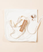Little Green Radicals hooded baby blanket in white. A 100% organic cotton hooded blanket folded into a square with decorative ribbon on top.