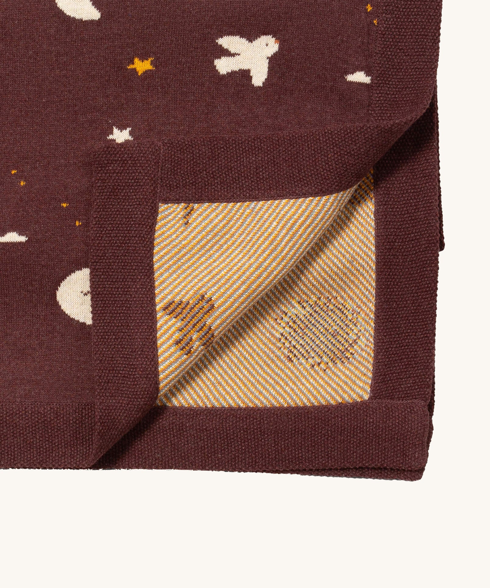 A close up of the Little Green Radicals baby blanket in flying birds. Showing the yellow striped embroidery inner liner on organic cotton fabric
