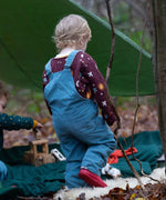 A child walking in the woods and wearing the Little Green Radicals pale blue lined corduory dungarees over the quilted flying birds sweater. Features 2 back pockets and adjustable shoulder straps.