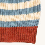 A close up of the Little Green Radicals knitted beanie in blue stripes. Showing the thick red knit brim detail on organic cotton fabric