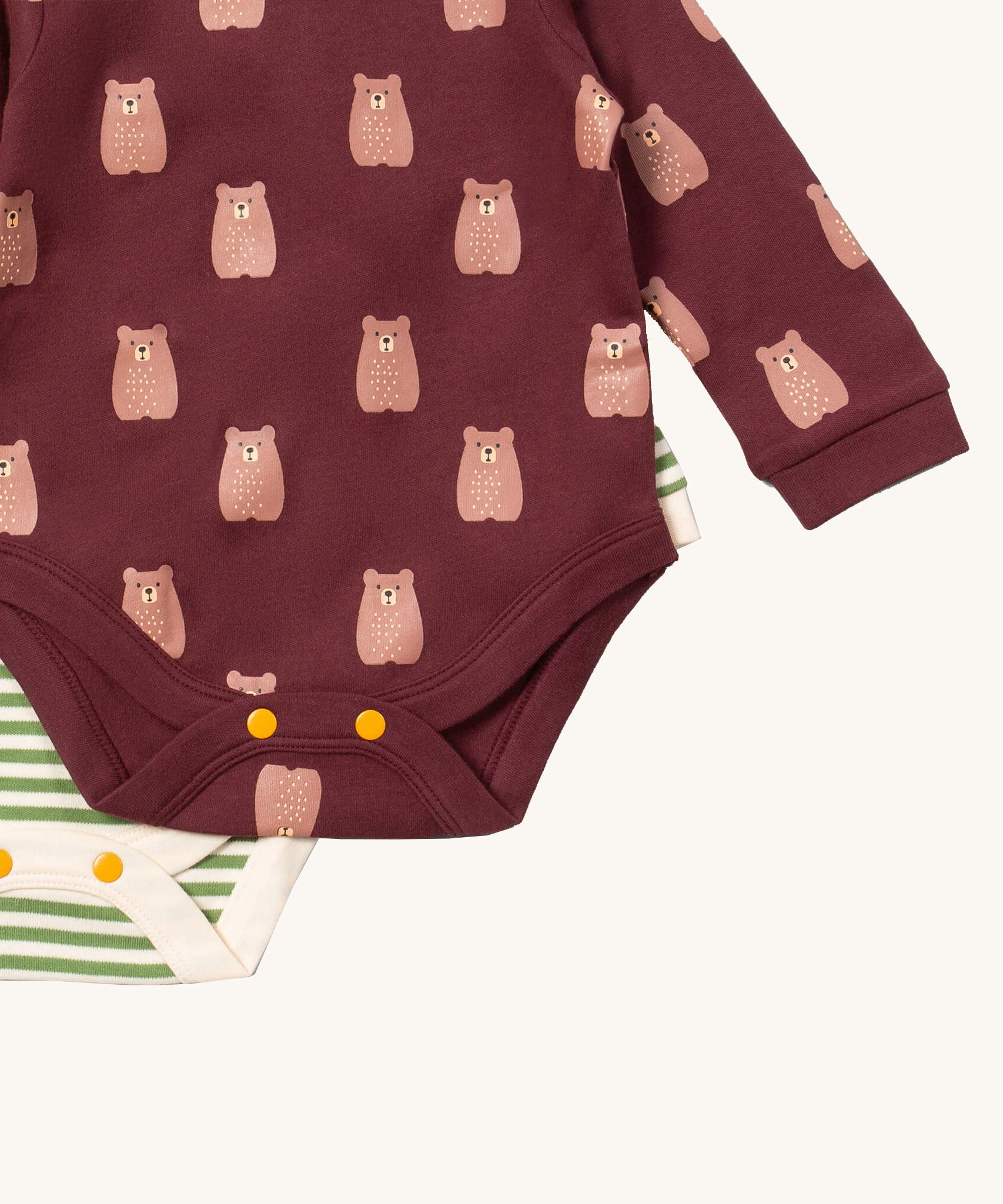 A close up of the striped Little Green Radicals baby body suit underneath the brown bear bodysuit showing yellow popper detail around the crotch and leg hole detail on soft organic cotton fabric
