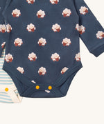 A close up of the sheep Little Green Radicals baby body suit on top of the light blue and cream striped bodysuit showing yellow popper detail around the crotch and leg hole detail on soft organic cotton fabric