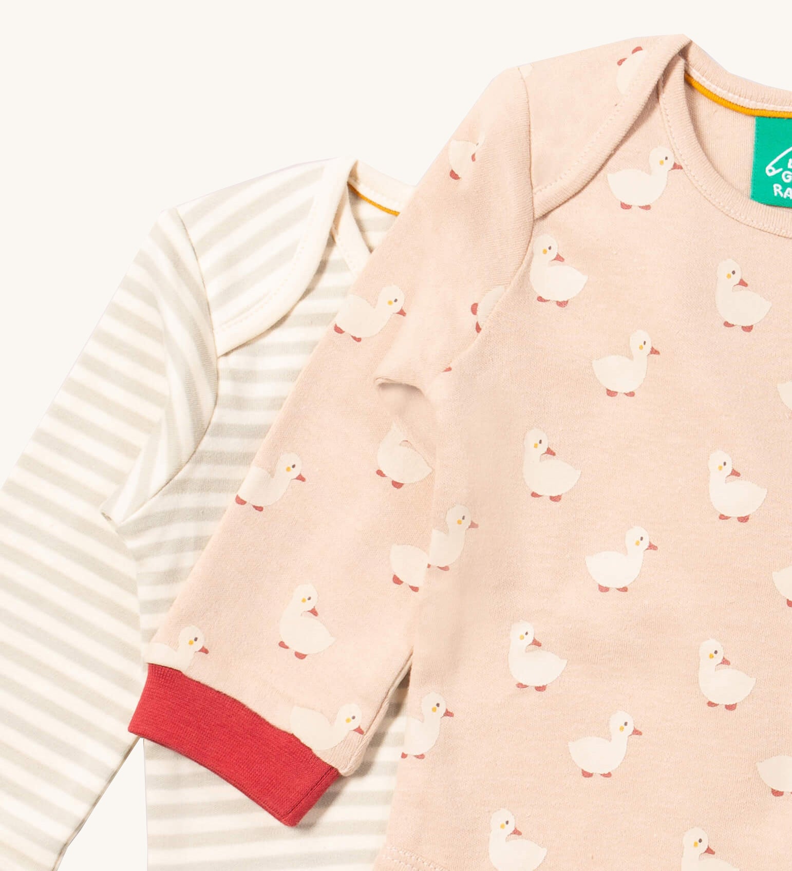 A close up of the duck Little Green Radicals baby body suit on top of the striped bodysuit showing red cuff trim and print detail on soft organic cotton fabric