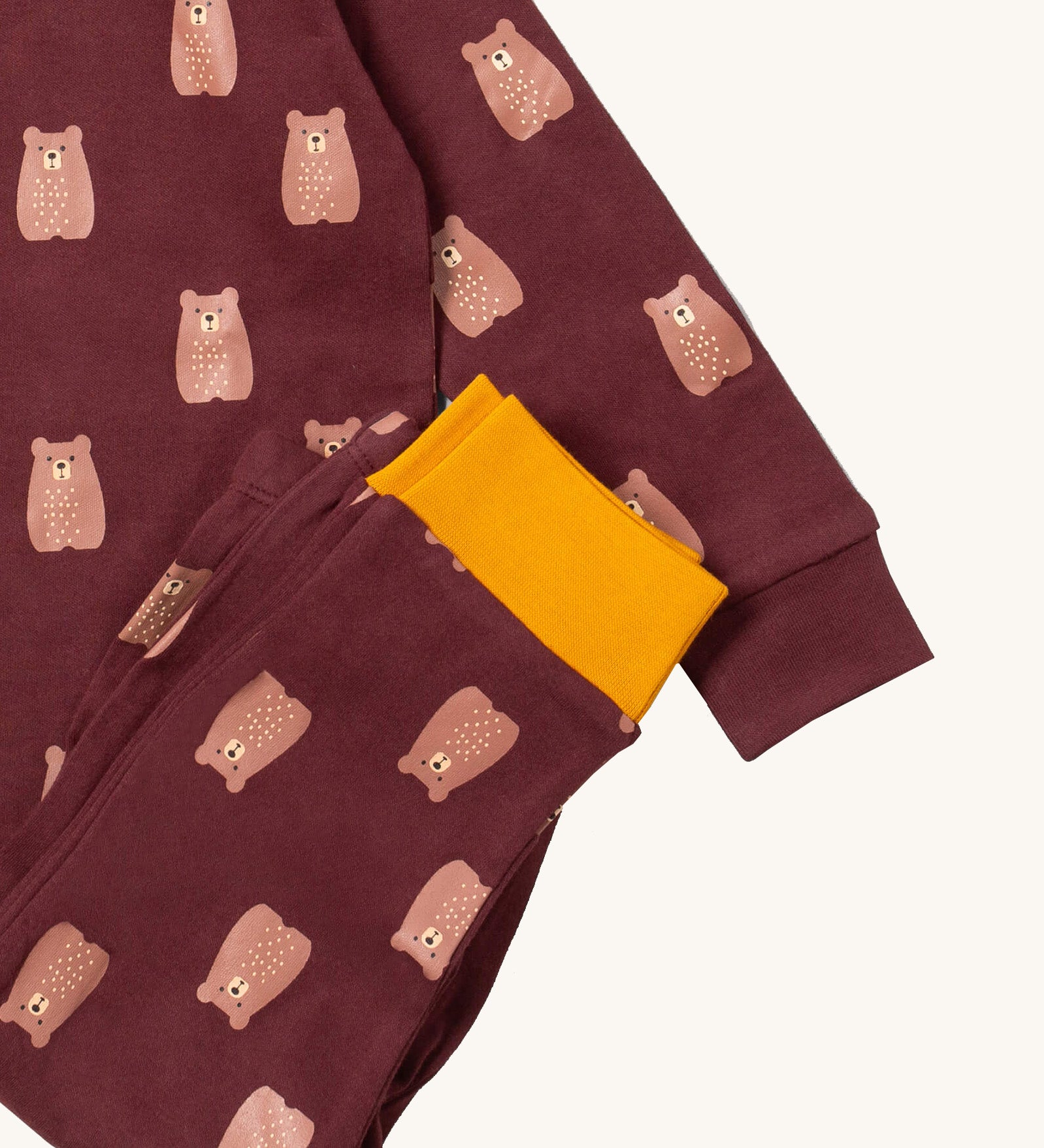 A close up of the Little Green Radicals brown bear pyjama set showing the brown with yellow trim bottom and brown bear detail on organic cotton fabric.