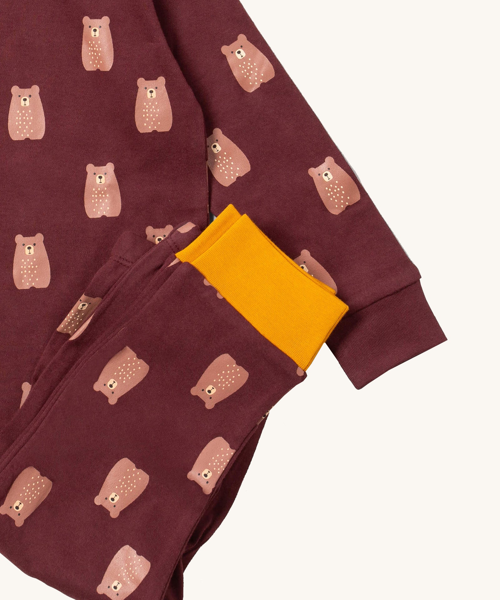 A close up of the Little Green Radicals brown bear pyjama set showing the brown with yellow trim bottom and brown bear detail on organic cotton fabric.