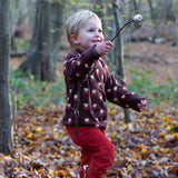 A child wearing the Little Green Radicals brown owl knitted jumper available at Babipur. A soft knit jumper with cute owls and thick cuffs for warmth on brown organic cotton fabric. 