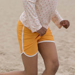 Close up of girl running in the LGR recycled yellow swimming shorts