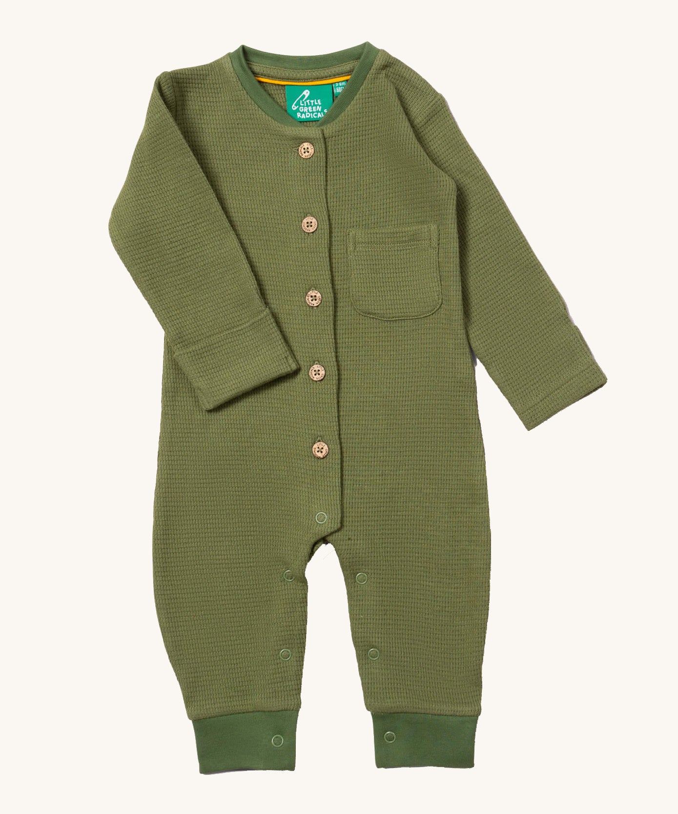 Little Green Radicals green chive waffle playsuit available at Babipur. A GOTS organic cotton all in one in a soft waffle knit style. Features button fasteners on the front and poppers around the crotch with a small pouch chest pocket and matching green trim