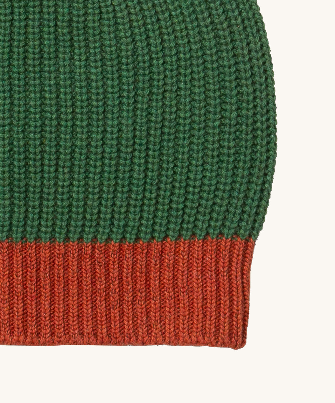 A close up of the Little Green Radicals knitted beanie in chive. Showing the thick red knit brim detail on organic cotton fabric