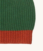 A close up of the Little Green Radicals knitted beanie in chive. Showing the thick red knit brim detail on organic cotton fabric