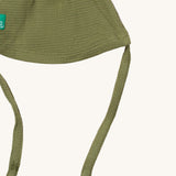 A close up of the Little Green Radicals chive waffle tie hat showing the tie strap for a secure fit and waffle knit detail on green organic cotton fabric