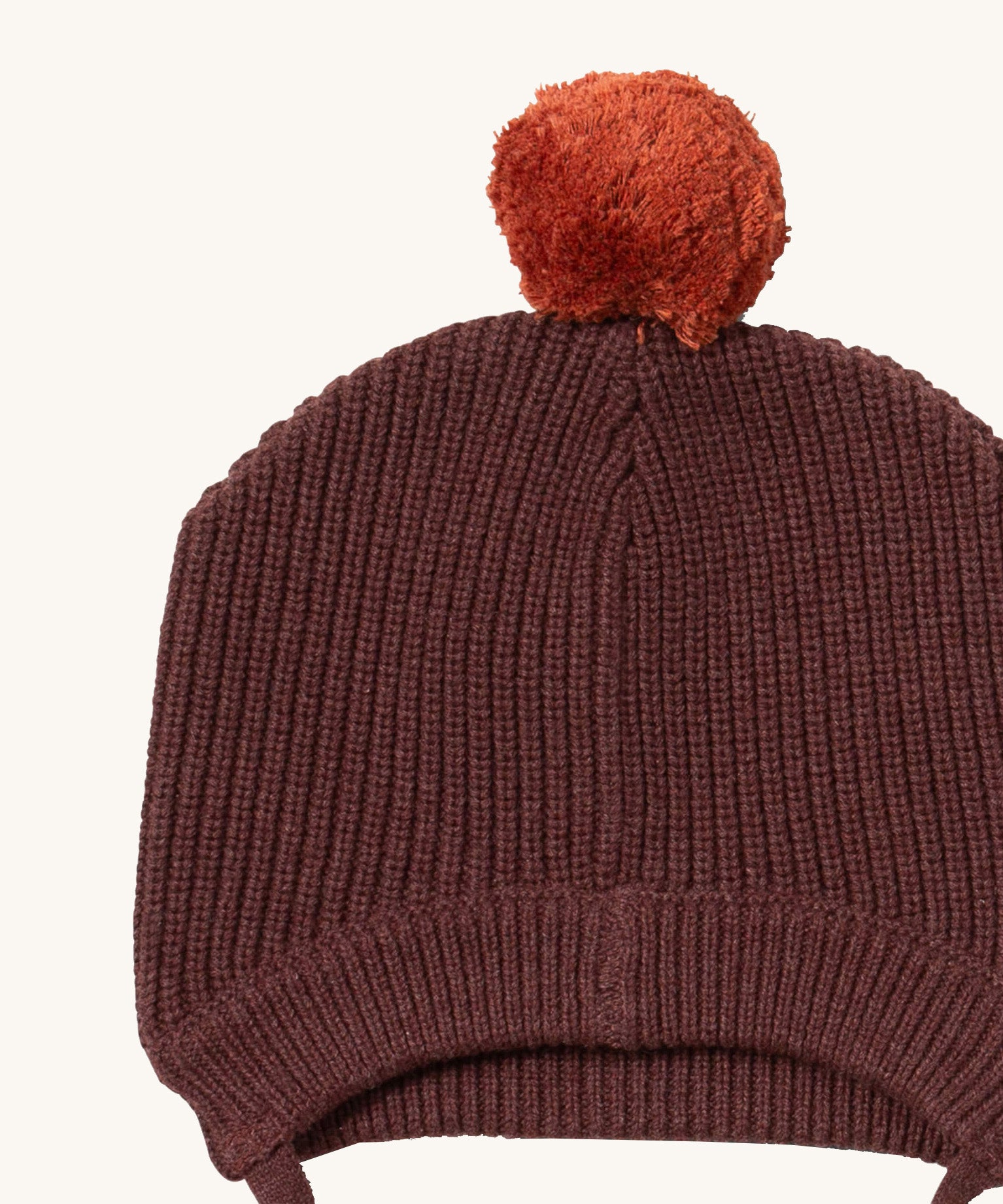 A close up of the Little Green Radicals chocolate knitted beanie hat showing the knit detail on brown organic cotton fabric.