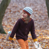 A child wearing the Little Green Radicals knitted cardigan in chocolate outside showing the length and fit of the cardigan 