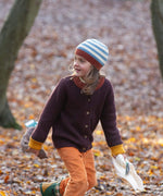 A child wearing the Little Green Radicals knitted cardigan in chocolate outside showing the length and fit of the cardigan 