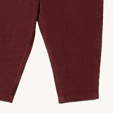 A close up of the Little Green Radicals comfy trousers in chocolate corduroy. Showing the corduroy detail on dark maroon organic cotton fabric