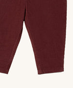 A close up of the Little Green Radicals comfy trousers in chocolate corduroy. Showing the corduroy detail on dark maroon organic cotton fabric