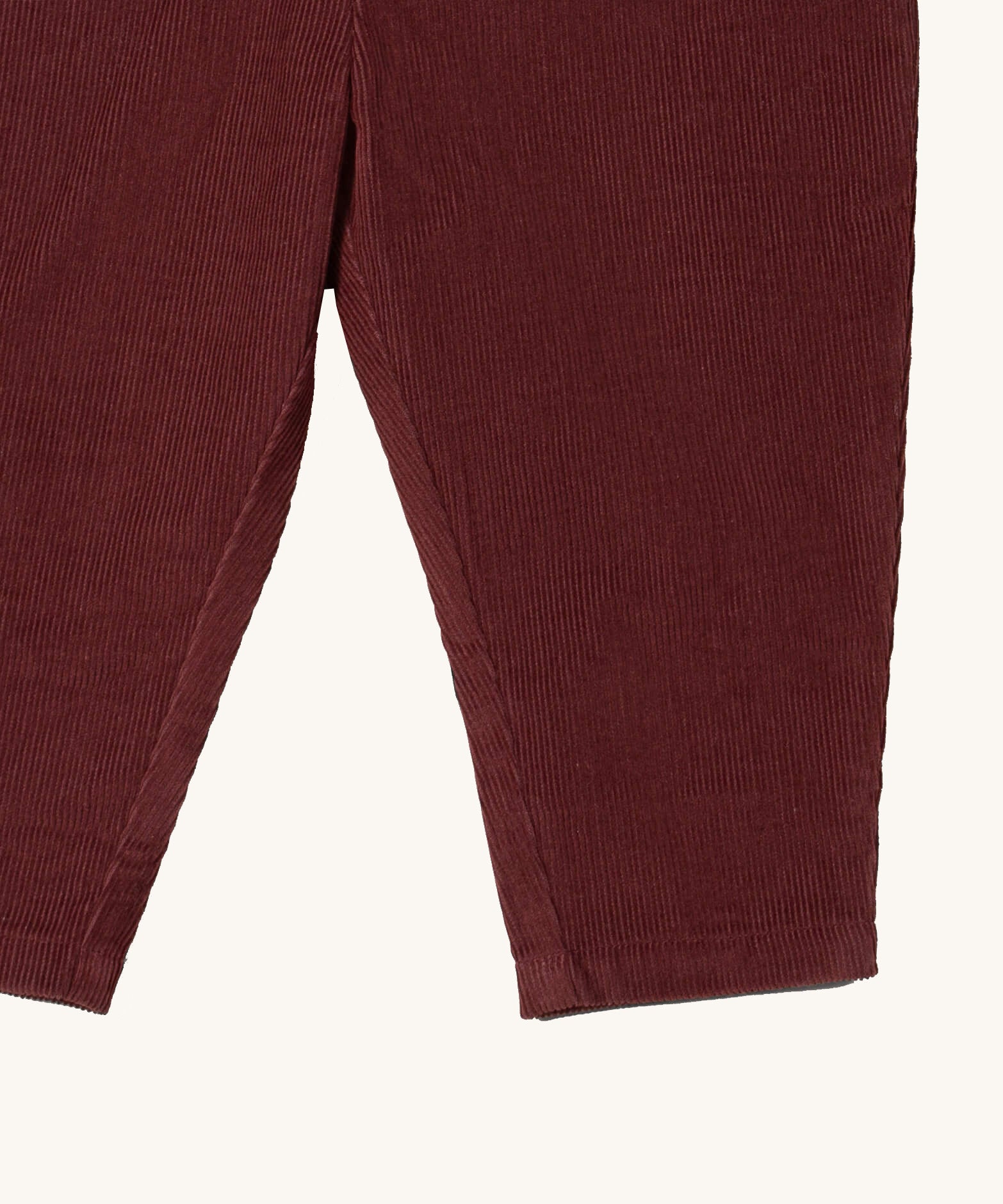 A close up of the Little Green Radicals comfy trousers in chocolate corduroy. Showing the corduroy detail on dark maroon organic cotton fabric